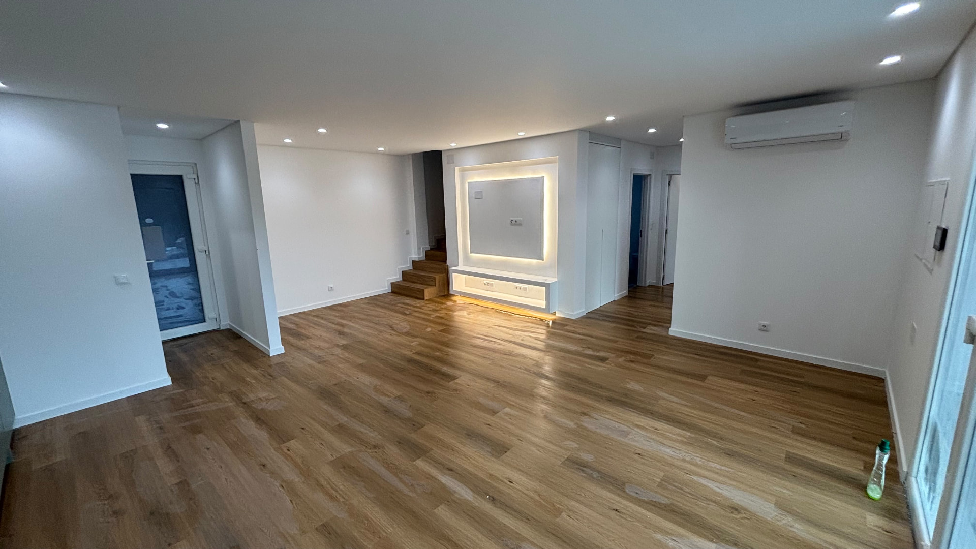 Sala ampla com piso flutuante e nicho de TV iluminado